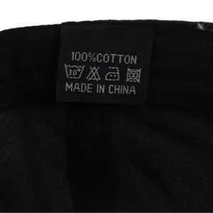 Detailed close-up of 100% cotton fabric and wash care label on black baseball cap