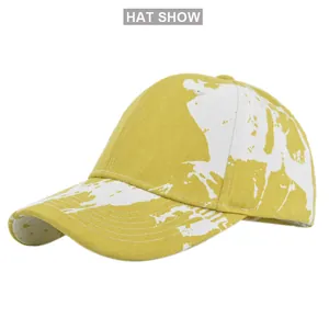 Close-up of yellow tie-dye cotton baseball cap featuring white splatter paint patterns