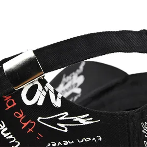 Dettaglio del cappellino in tela nera con ricamo graffiti e fibbia in metallo argentato