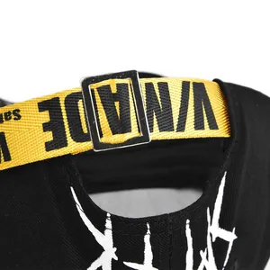 Close-up of black baseball cap featuring yellow V-WADE strap and silver metal buckle