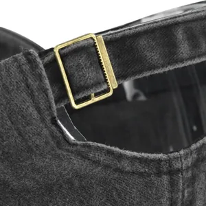 Dettaglio della fibbia in ottone vintage e del tessuto di lana grigia del cappello