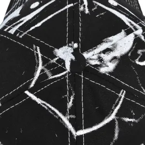 Macro view of top button and stitching details on a black tie-dye skull baseball cap