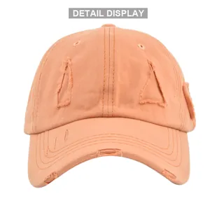 Close-up of distressed vintage orange cotton baseball cap showing rip details and texture