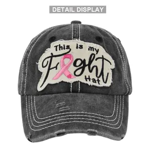 Detalle de gorra de béisbol gris desgastada con bordado de lazo rosa y estilo retro