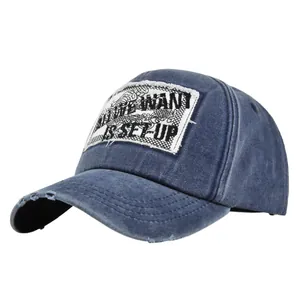 Close-up of distressed denim baseball cap with ALL WE WANT IS SET-UP slogan embroidery