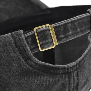 Détail de la boucle en laiton ajustable sur la casquette en toile noire délavée