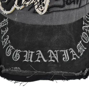 Close-up of gothic embroidery and distressed washed canvas texture on a vintage baseball cap
