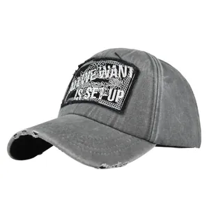 Close-up of distressed grey baseball cap with embroidered vintage fabric patch and frayed brim