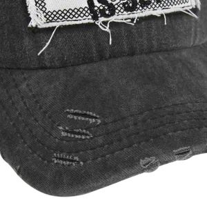 Close-up of distressed brim and patch detail on washed black cotton baseball cap