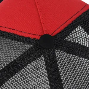 Detail of red twill and black mesh panels on a breathable trucker hat with top button