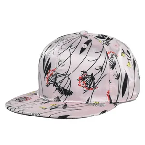 Detail of pink satin flat brim snapback cap featuring black floral patterns and embroidery