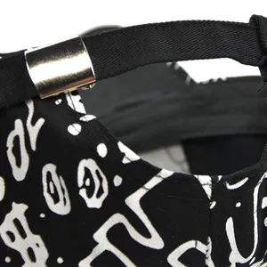 Dettaglio del cappellino nero con stampa graffiti bianca e fibbia in metallo argento