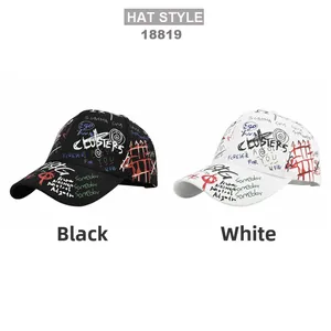 Close-up of black and white baseball caps with all-over graffiti print and 3D embroidery