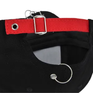 Détail d'une casquette noire montrant la sangle réglable rouge et la boucle en métal