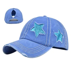 Dettaglio cappello da baseball in denim blu con paillettes a stella e ricami consumati