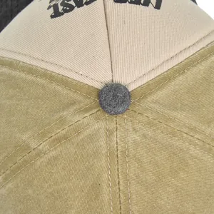 Close-up of the khaki and beige baseball cap crown with button and embroidery details
