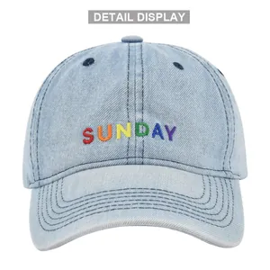 Detail showing rainbow SUNDAY embroidery on light blue washed denim baseball cap