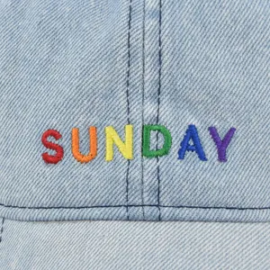 Front view of light blue denim baseball cap featuring colorful SUNDAY embroidery