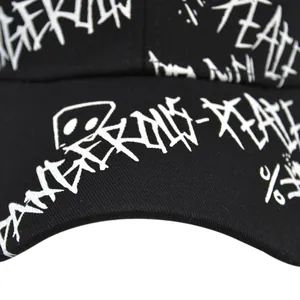 Détail rapproché d'imprimés graffitis blancs sur le sergé de coton noir de la casquette