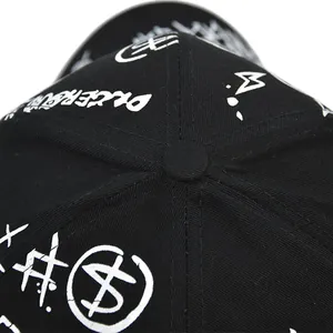 Détail du bouton supérieur et des coutures de la casquette de baseball noire avec graffiti