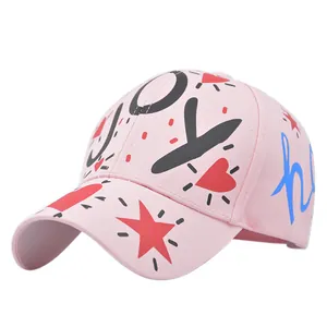 Detail of pink cotton baseball cap with JOY graffiti print and red star embroidery
