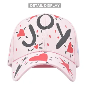 Detail display of pink cotton baseball cap featuring black JOY text and red heart prints