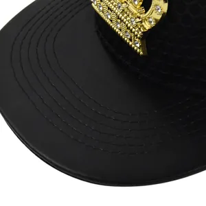 Macro detail of golden crown metal logo with rhinestones on a black leather cap brim