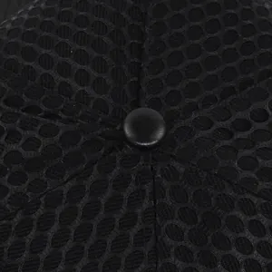 Macro detail of breathable hexagonal mesh fabric and round top button on the black trucker hat
