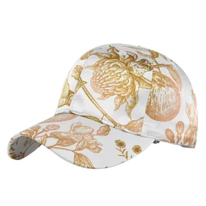 Close-up of golden floral prints on white baseball cap with refined curved brim