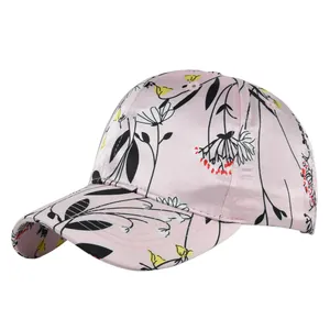Detailed close-up of light pink satin baseball cap with elegant floral line art and embroidery