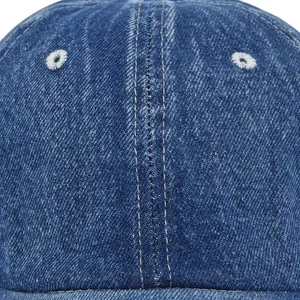 Close-up of blue denim baseball cap showing white stitching and embroidered eyelets