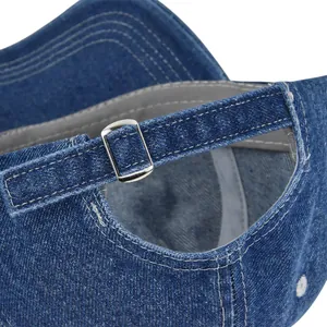 Detail of blue denim baseball cap featuring adjustable silver metal buckle and white stitching