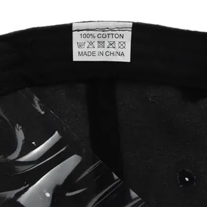 Detail view of the 100% cotton wash care label inside a black embroidered baseball cap