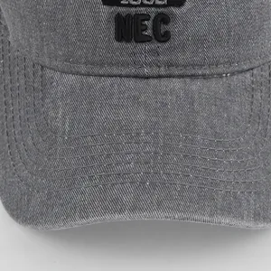 Dettaglio ravvicinato del cappellino grigio lavato con ricamo NEC 1988 sulla visiera