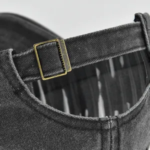 Detail view of washed denim baseball cap back strap with vintage brass metal buckle adjustment