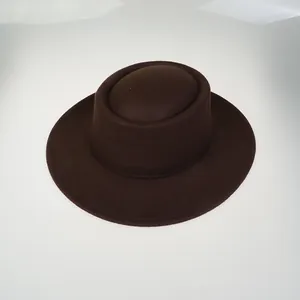 Top-down macro view of dark brown wool felt flat top fedora hat with fine texture