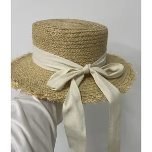 Elegant flat top raffia sun hat with fringed brim and cream bow for summer beach vacation