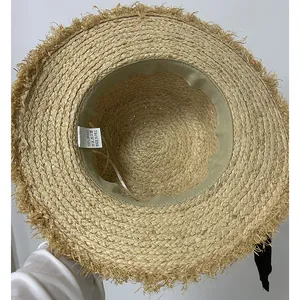 Detail view of woven raffia sun hat showing 100% grass material label and inner texture