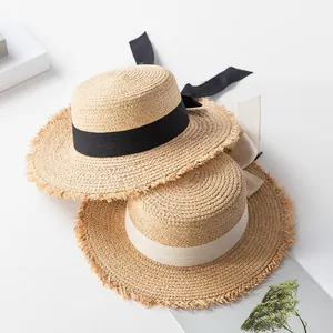 Detailed close-up of woven raffia boater hats featuring chic frayed edges and elegant ribbons