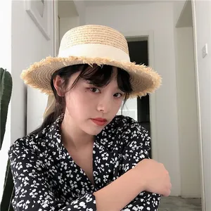 Detail of raffia straw sun hat with fringe edge and white ribbon for summer beach vacation