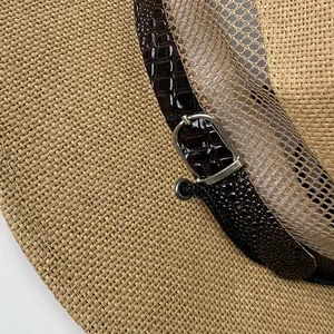 Detail of khaki straw sun hat featuring breathable mesh stitching and brown leather strap