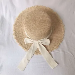 Elegant wide brim raffia straw hat with bow and fringe details for beach sun protection