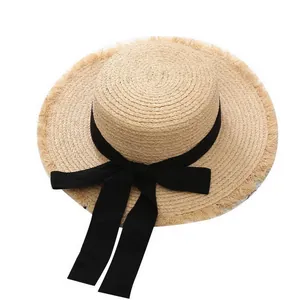 Detail of raffia boater hat with a black ribbon bow and frayed edge trim