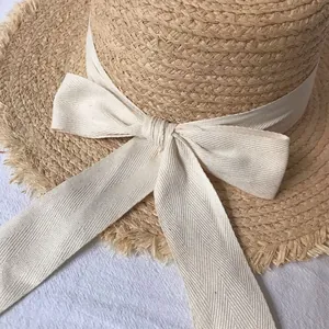 Detailed macro view of the raffia sun hat featuring frayed edges and a white bow ribbon