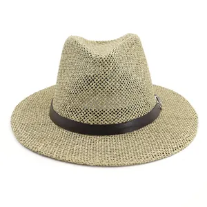 Detail of woven straw fedora hat texture with a brown faux leather belt and buckle