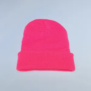 Detail of bright pink rib-knit winter beanie showing soft texture and folded cuff edge