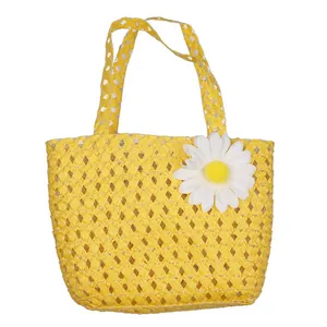 Macro shot of yellow hand-woven straw handbag with white daisy and metallic fiber accents