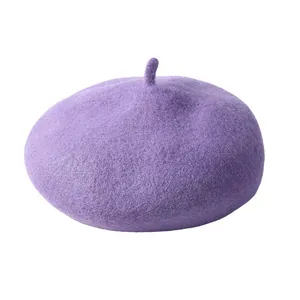 Gros plan du béret en laine violette montrant la texture lisse et le détail typique du haut