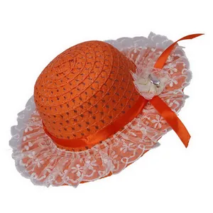 Detail of orange woven straw sun hat with white lace brim and decorative mesh flower
