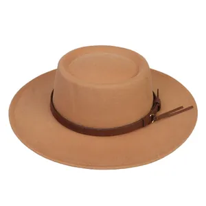 Detail of camel wool fedora hat featuring flat top and brown leather band with tassels
